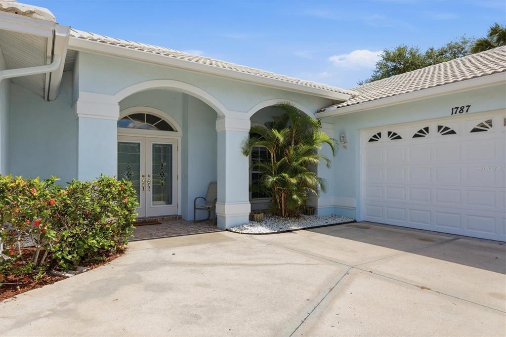 A light blue house exterior features a covered entryway, double front doors, and a garage — 1787 KILRUSS DRIVE, VENICE, FL