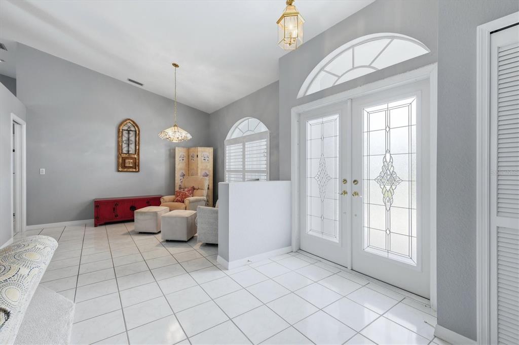 A bright entryway features white tile floors, double glass-paneled doors, and a small seating area — 1787 KILRUSS DRIVE, VENICE, FL