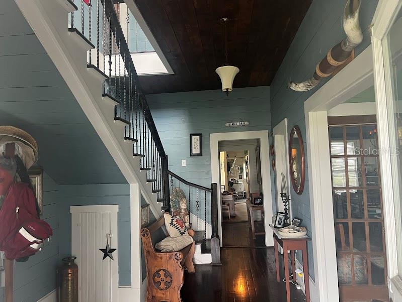 A foyer features a wooden staircase, blue shiplap walls, a dark wood ceiling, and a bench — 523 N LEE AVENUE, ARCADIA, FL