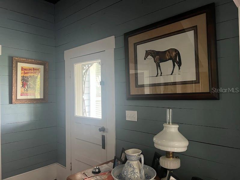A room with blue horizontal wood-plank walls, a white door, and framed wall art — 523 N LEE AVENUE, ARCADIA, FL