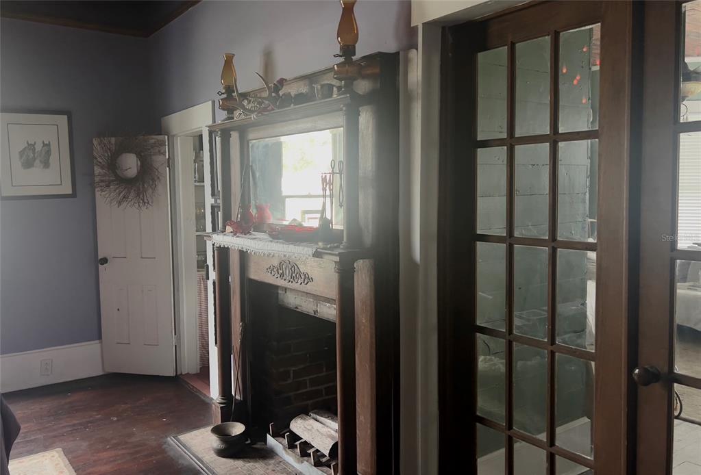 A room features a wooden fireplace mantel with a mirror, brick hearth, and glass-paned doors — 523 N LEE AVENUE, ARCADIA, FL