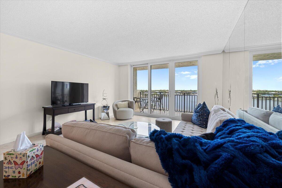 A living room features a sectional sofa, a television, and a balcony with water views — 3912 S Ocean Boulevard # 603, Highland Beach FL 33487, HIGHLAND BEACH, FL