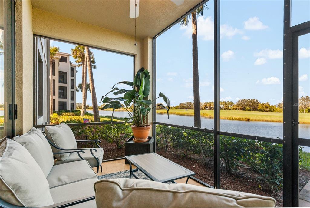 A screened-in porch features patio furniture and views of a pond and golf course — 7121 RIVER HAMMOCK DRIVE UNIT 102, BRADENTON, FL
