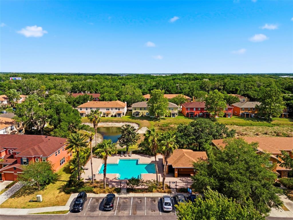 An aerial view shows a community swimming pool surrounded by townhomes, trees, and parking spaces — 6811 DARTMOUTH HILL STREET, RIVERVIEW, FL