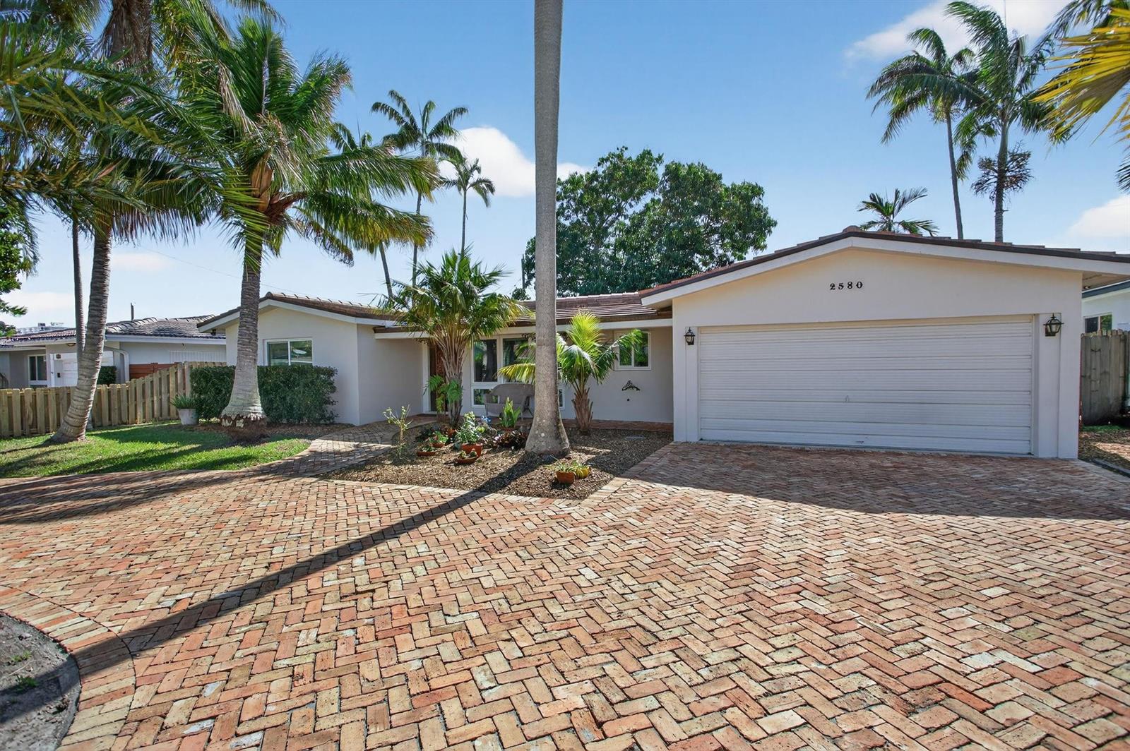 A single-story house with a brick driveway, palm trees, and a two-car garage — 2580 SE 5th Court, Pompano Beach FL 33062, POMPANO BEACH, FL