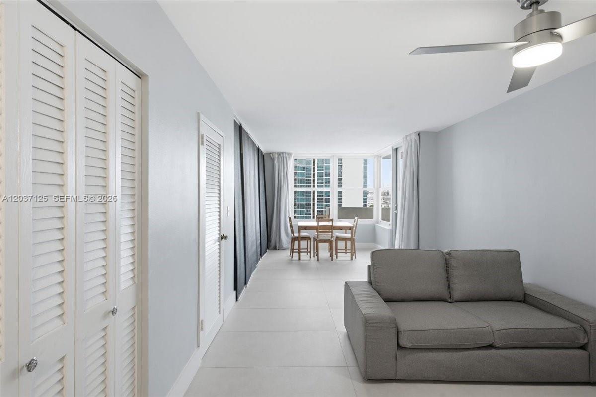 A living room features light gray walls, tile flooring, a gray sofa, and a dining set — 2899 Collins Ave # 1022, Miami Beach FL 33140, MIAMI BEACH, FL
