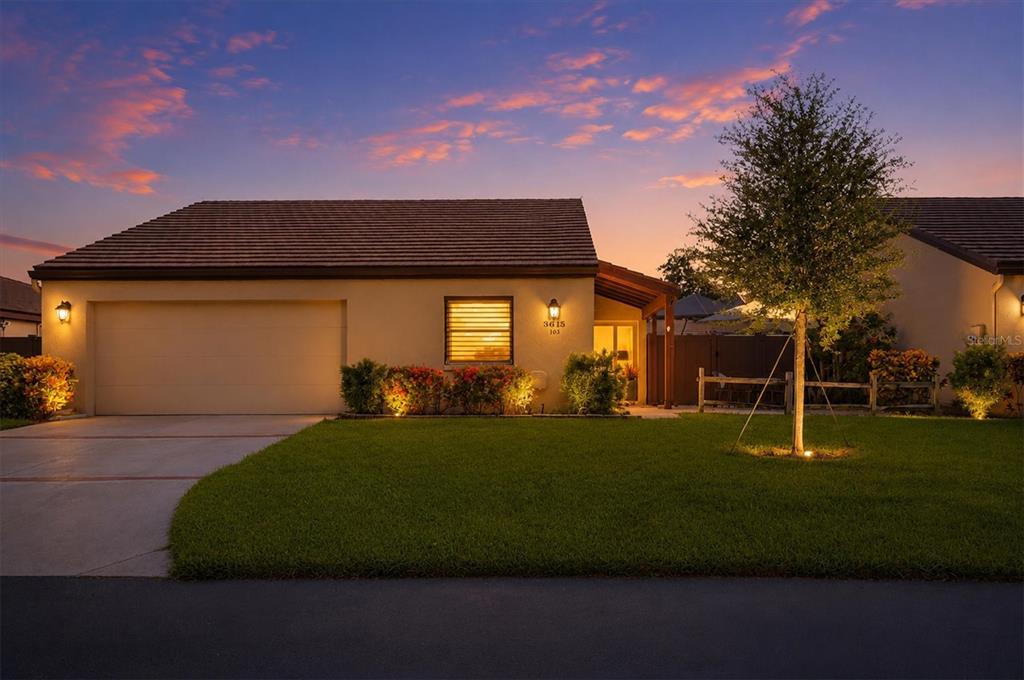 A single-story house with a tan stucco exterior, a two-car garage, and a front lawn — 3615 GLEN OAKS MANOR DRIVE, SARASOTA, FL