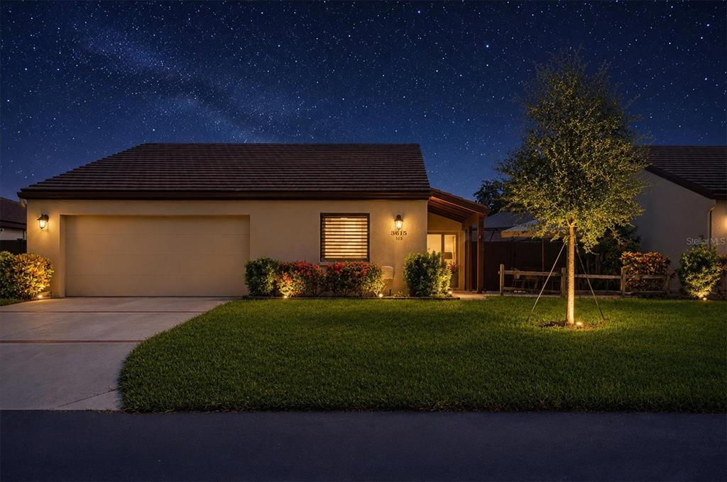 A single-story house with a garage and illuminated landscaping under a starry night sky — 3615 GLEN OAKS MANOR DRIVE, SARASOTA, FL