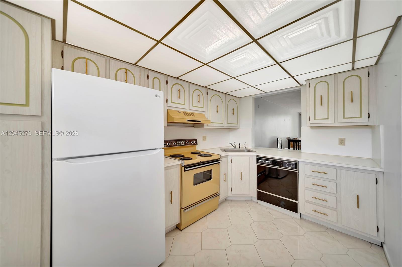 A kitchen features white cabinets, a yellow stove and range hood, and a drop ceiling — 2571 Aragon Blvd # 220, Sunrise FL 33322, SUNRISE, FL