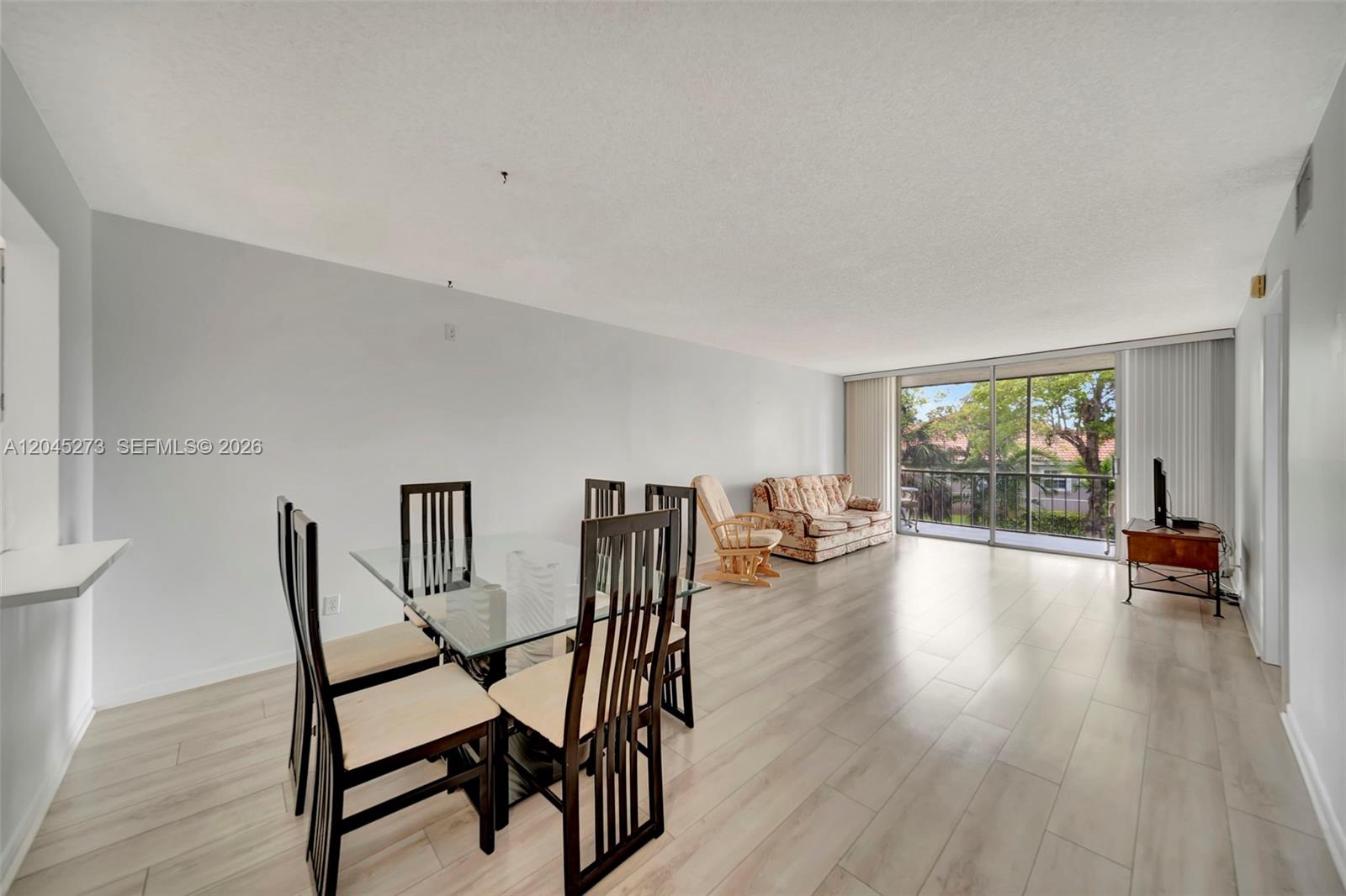 A dining area and living space feature light wood-look flooring and a sliding glass door — 2571 Aragon Blvd # 220, Sunrise FL 33322, SUNRISE, FL