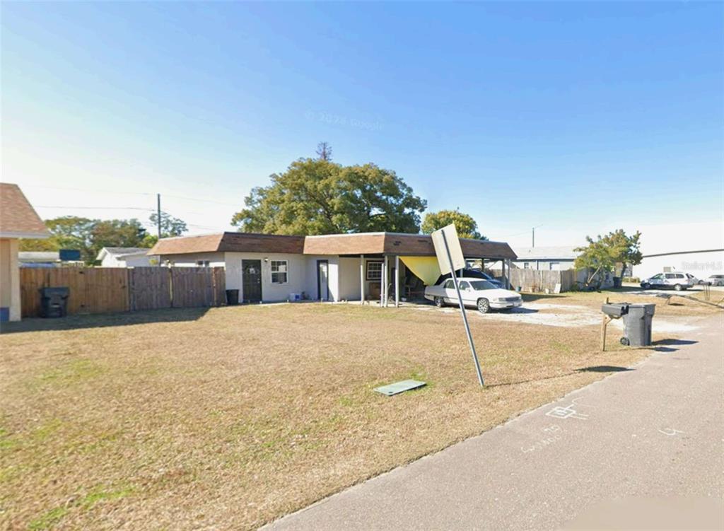 A single-story house with a flat roof and attached carport sits behind a large lawn — 4130 32ND STREET N, ST PETERSBURG, FL