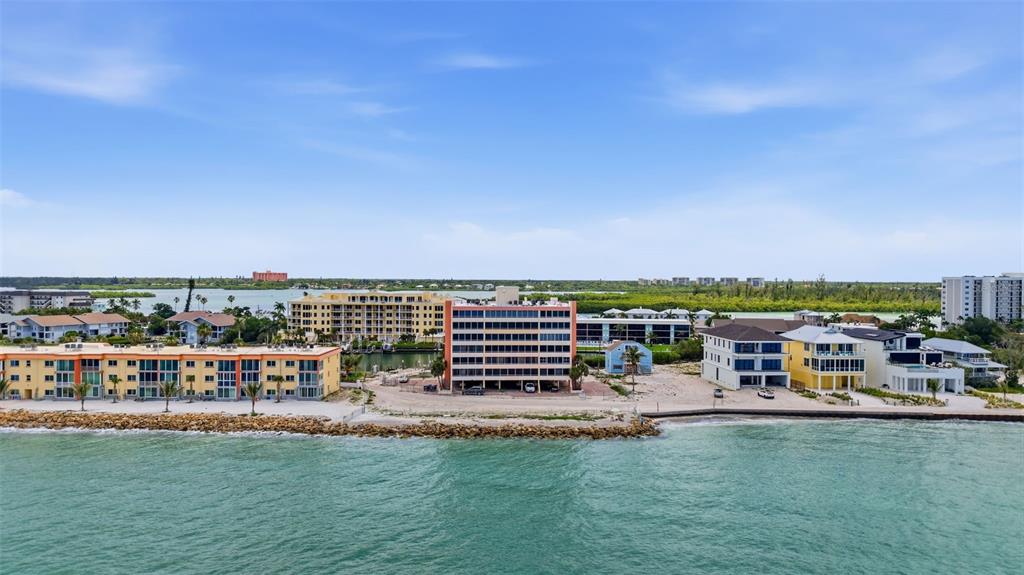 An aerial view shows a coastal residential area with multi-story apartment buildings and houses — 9150 BLIND PASS ROAD UNIT 206, SARASOTA, FL