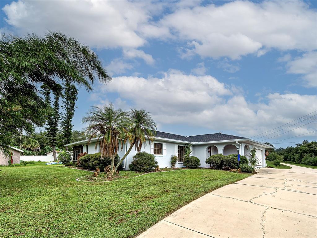 A single-story house with a white exterior, a dark roof, and palm trees in the yard — 1181 SEACREST DRIVE NW, PORT CHARLOTTE, FL