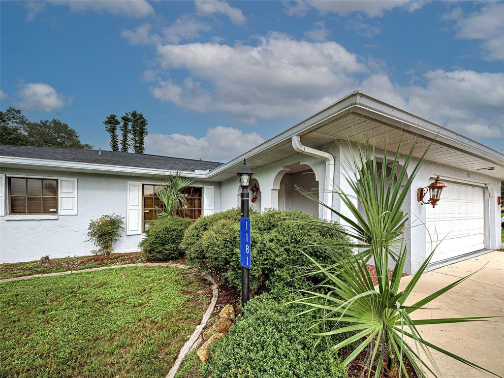 A single-story house features a white stucco exterior, a garage, and a front lawn — 1181 SEACREST DRIVE NW, PORT CHARLOTTE, FL