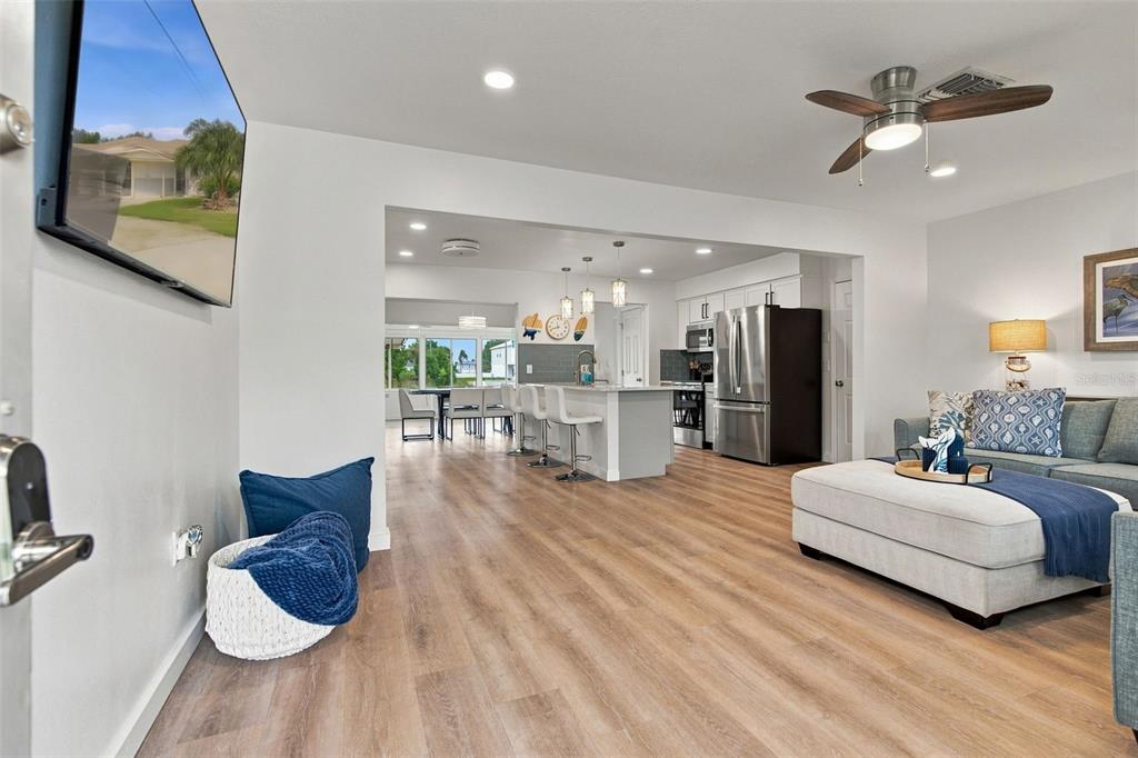 An open-concept living room and kitchen feature light wood flooring and a large sectional sofa — 3339 POINSETTIA DRIVE, HERNANDO BEACH, FL