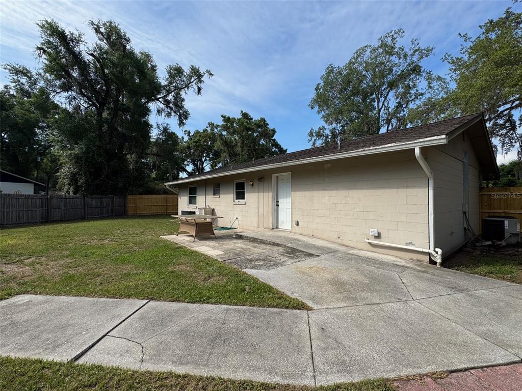 A single-story house with a garage, stone accents, and a large lawn under trees — 6052 IDLE A WHILE CIRCLE, DADE CITY, FL
