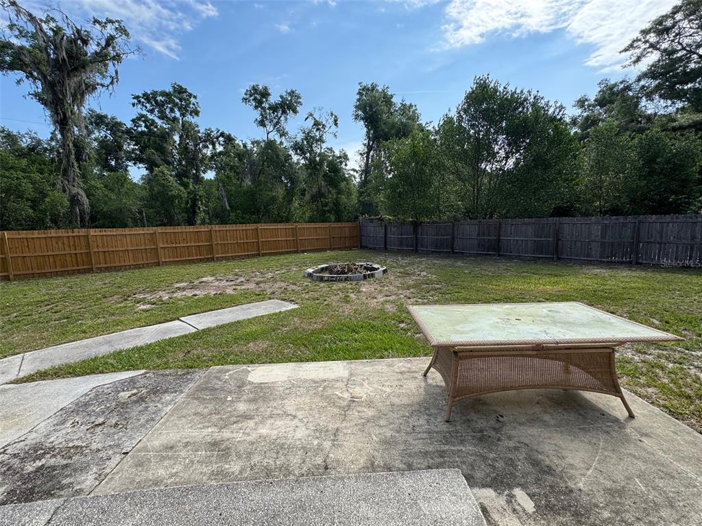 A backyard features a concrete patio, a small brick area, and a wooden privacy fence — 6052 IDLE A WHILE CIRCLE, DADE CITY, FL