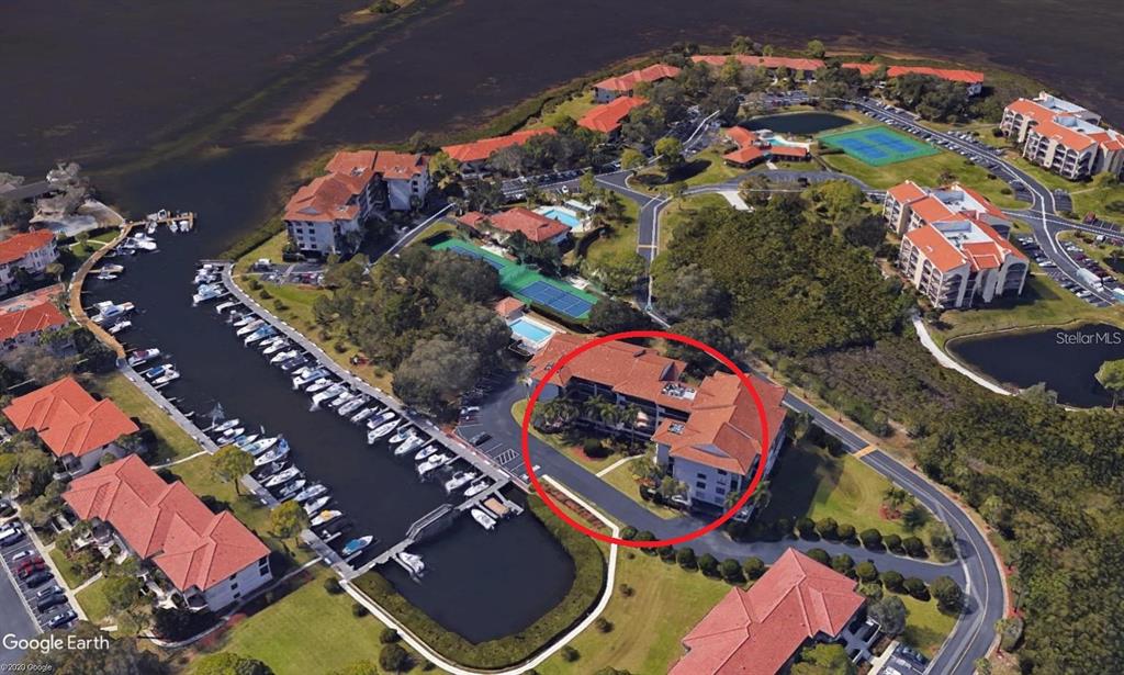 An aerial view shows a multi-story residential building circled in red within a waterfront complex — 1806 MARINER DRIVE UNIT 214, TARPON SPRINGS, FL