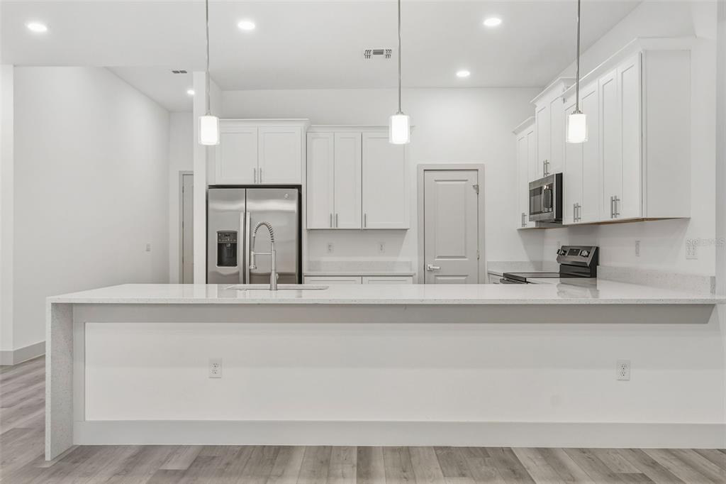 A modern kitchen features white cabinets, stainless steel appliances, and a large quartz-topped island — 18024 PLACID AVENUE, PORT CHARLOTTE, FL