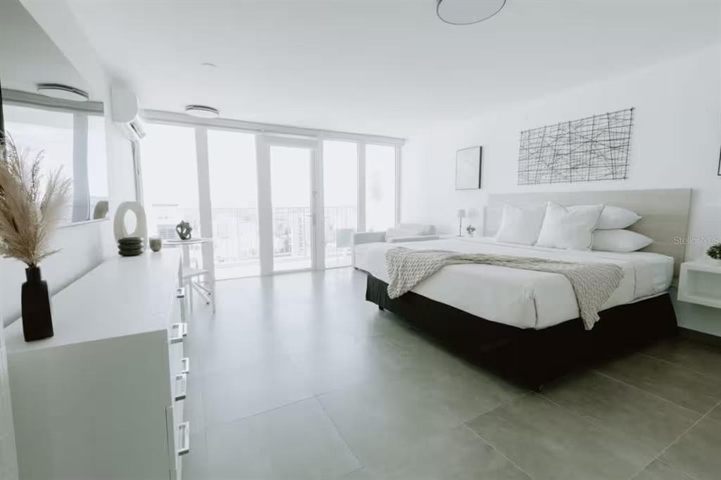 A modern bedroom features white walls, tile flooring, a large bed, and floor-to-ceiling glass doors — 6165 AV. ISLA VERDE UNIT 1052, CAROLINA, PR