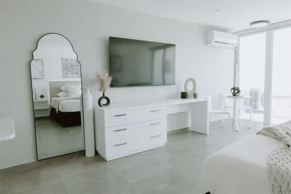 A modern bedroom features a white dresser, a wall-mounted television, and a large arched mirror — 6165 AV. ISLA VERDE UNIT 1052, CAROLINA, PR