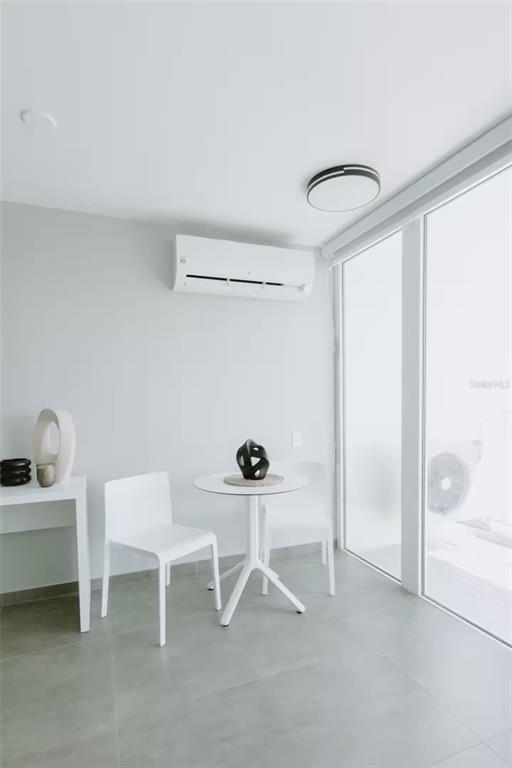 A minimalist dining area features a small round table, two white chairs, and wall-mounted air conditioning — 6165 AV. ISLA VERDE UNIT 1052, CAROLINA, PR