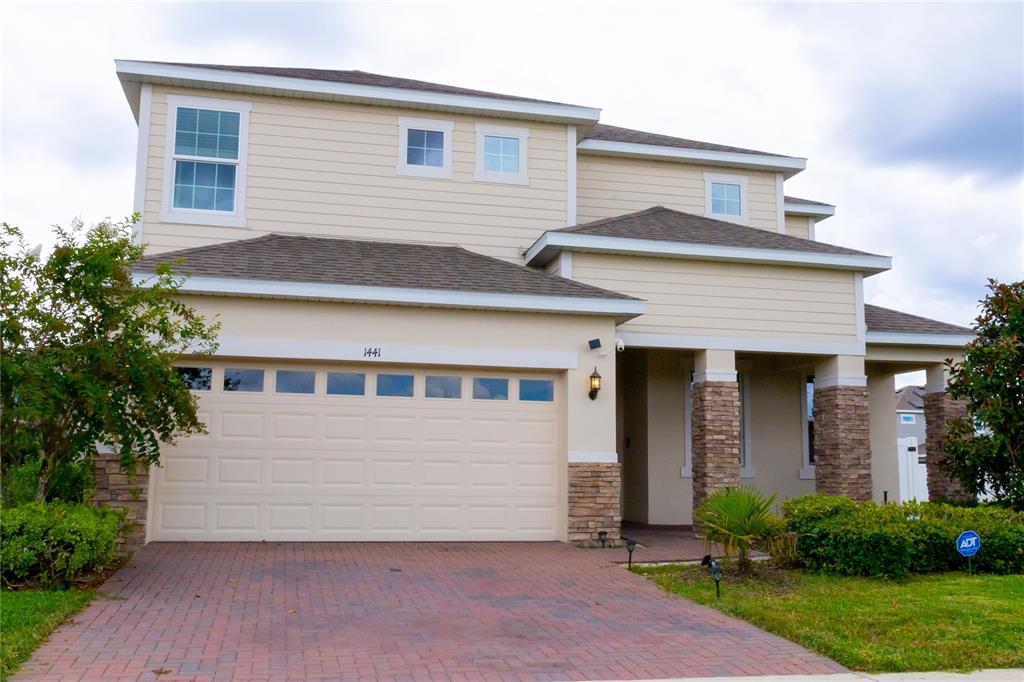 A two-story house with beige siding, a brick driveway, and a two-car garage — 1441 ROSEDALE ROAD, DAVENPORT, FL