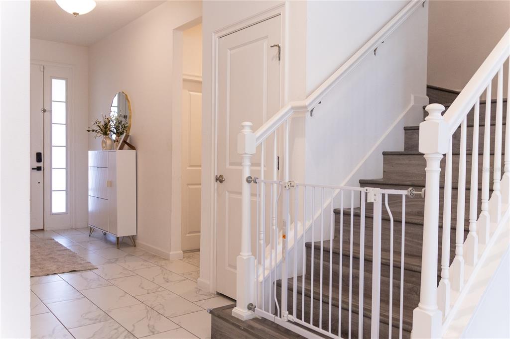 A white baby gate is installed at the base of a staircase with wood-look steps — 1441 ROSEDALE ROAD, DAVENPORT, FL