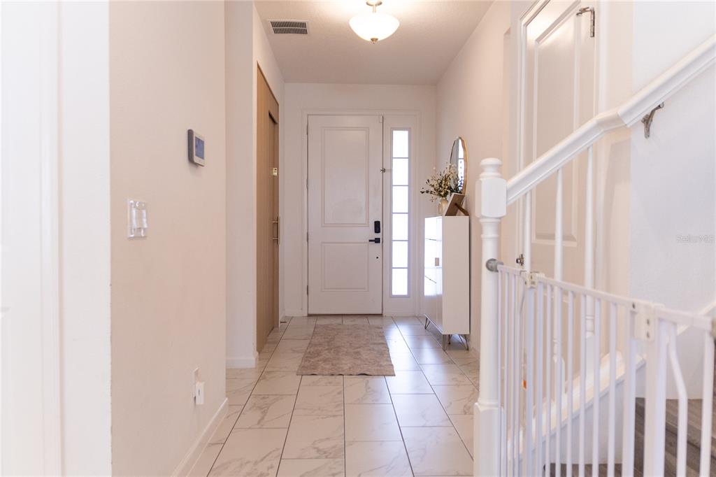 A bright entryway features white tile flooring, a front door with sidelights, and a staircase — 1441 ROSEDALE ROAD, DAVENPORT, FL