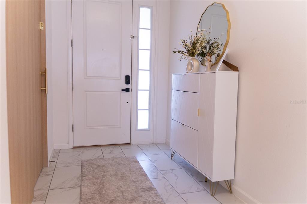 An entryway features white tile floors, a white door, and a modern white storage cabinet — 1441 ROSEDALE ROAD, DAVENPORT, FL