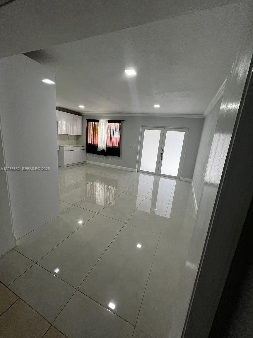 A bright, open-concept room features white tile flooring, recessed lighting, and a small kitchen area — 1271 W 79th St, Hialeah FL 33014, HIALEAH, FL