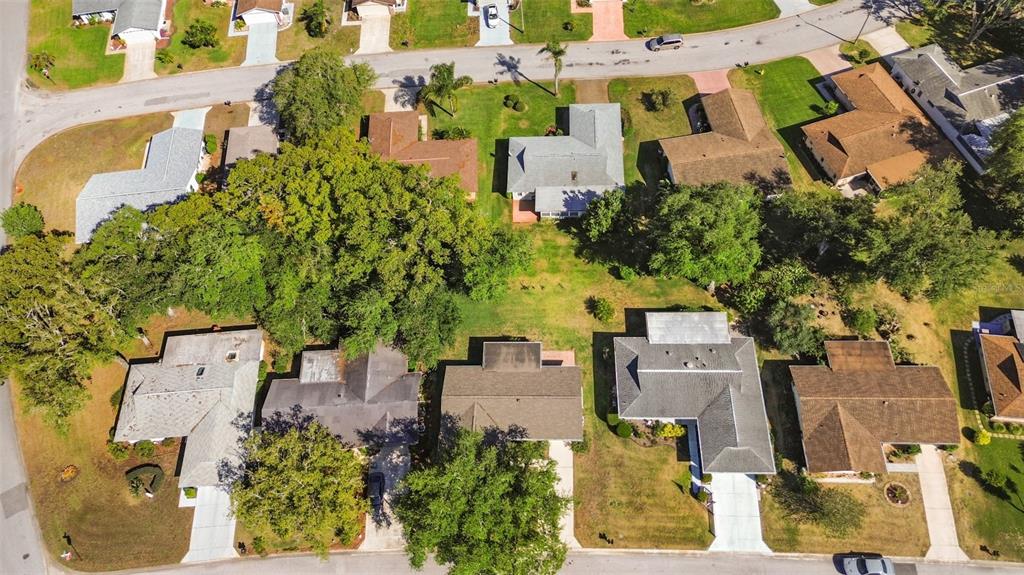 An aerial view shows several suburban houses with driveways surrounded by trees and grassy lawns — 10616 SPRINGWOOD DRIVE, PORT RICHEY, FL