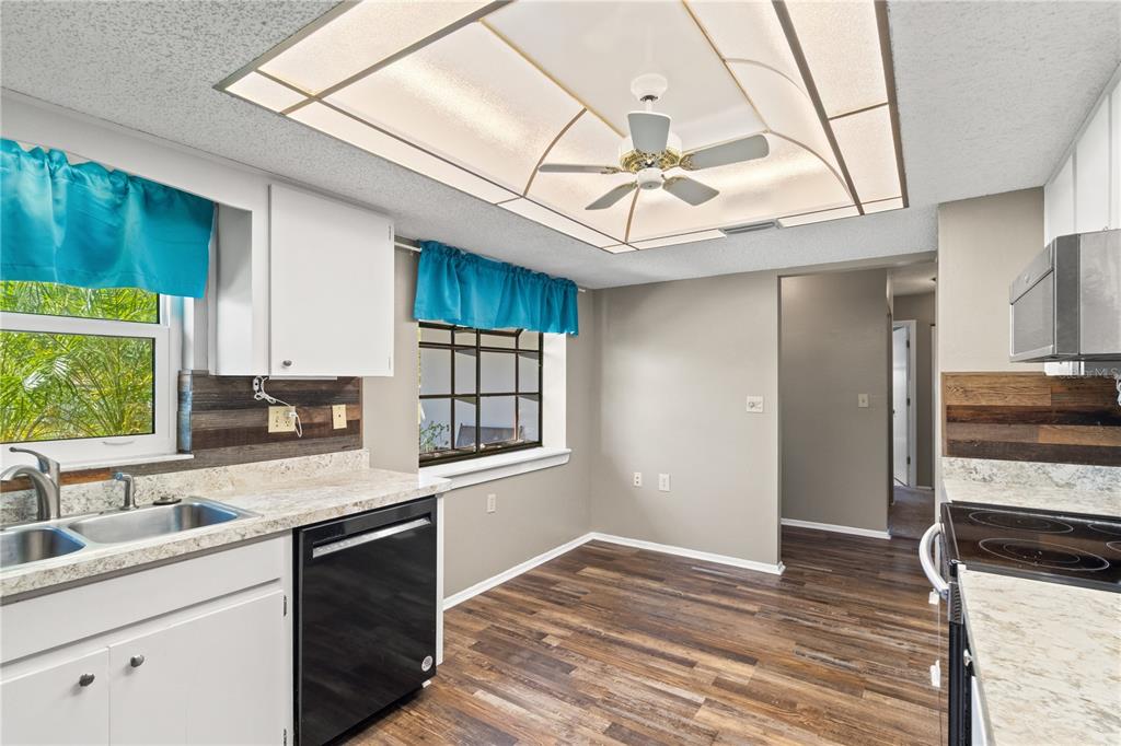 A kitchen with wood-look flooring, white cabinets, a ceiling fan, and a black dishwasher — 10616 SPRINGWOOD DRIVE, PORT RICHEY, FL