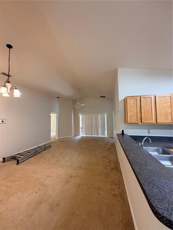 An open-concept living area features tan carpeting, a kitchen counter, and a dining light fixture — 175 RIDGEBROOK COURT, DAVENPORT, FL