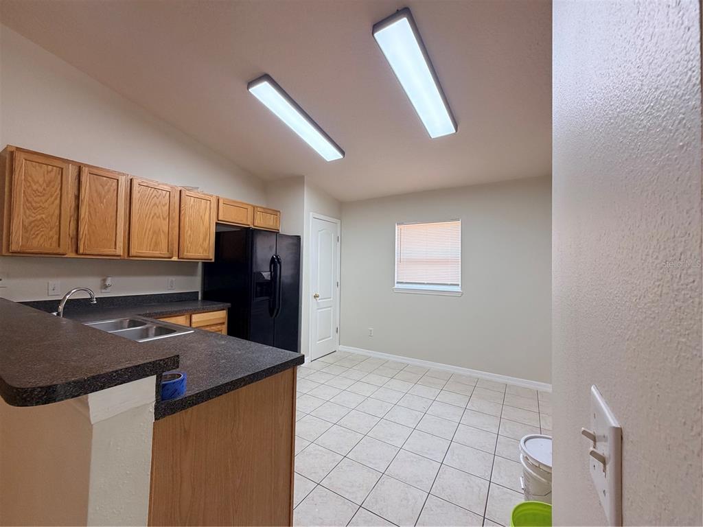 A kitchen features oak cabinets, black appliances, a double sink, and light-colored floor tiles — 175 RIDGEBROOK COURT, DAVENPORT, FL