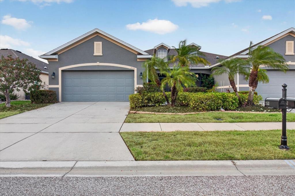 A gray single-story house with a two-car garage, palm trees, and a landscaped front yard — 2153 BARRACUDA COURT, HOLIDAY, FL