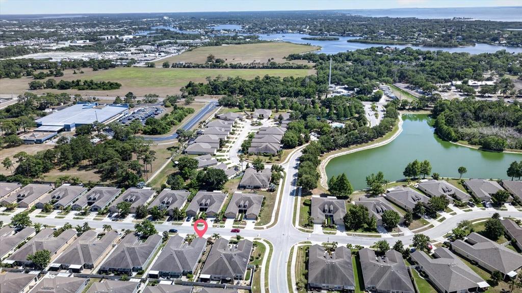 An aerial view shows a residential neighborhood with houses, a pond, and nearby commercial buildings — 2153 BARRACUDA COURT, HOLIDAY, FL