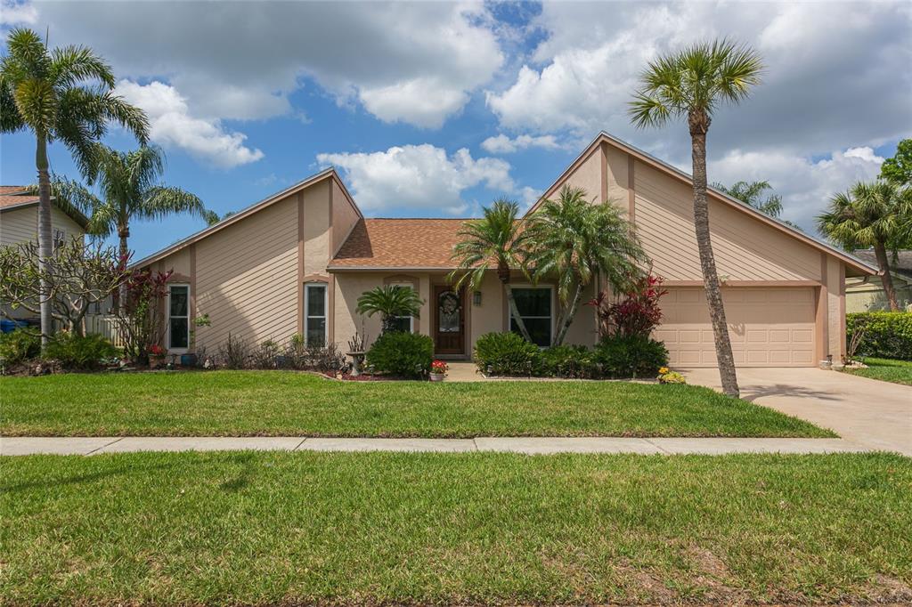 A single-story tan house with a two-car garage and palm trees in the front yard — 6104 SCHOONER WAY, TAMPA, FL
