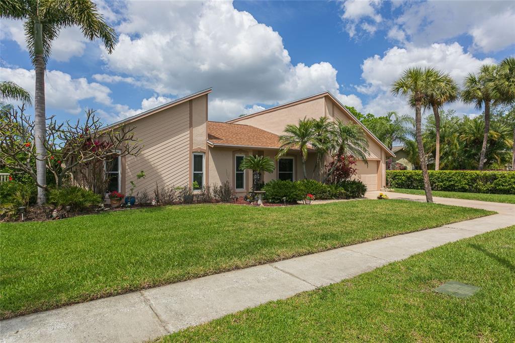 A single-story house with tan siding, a brown shingled roof, and palm trees in front — 6104 SCHOONER WAY, TAMPA, FL