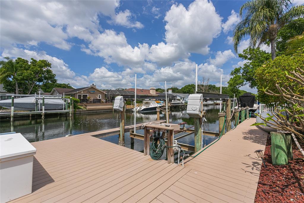 A wooden boat dock with a boat lift sits on a canal near houses — 6104 SCHOONER WAY, TAMPA, FL