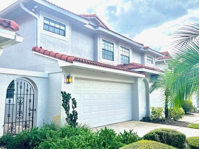 A two-story house exterior with a white stucco facade, red tile roof, and garage — 8214 AMBROSE COVE WAY, ORLANDO, FL