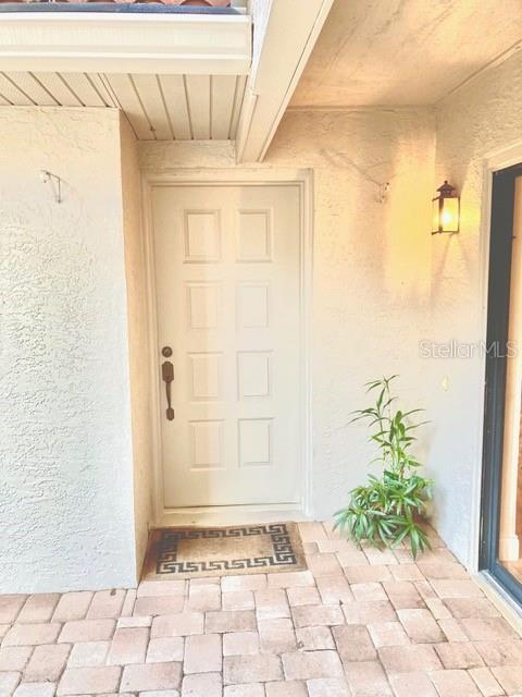 A white front door with a decorative rug sits on a paved entryway — 8214 AMBROSE COVE WAY, ORLANDO, FL