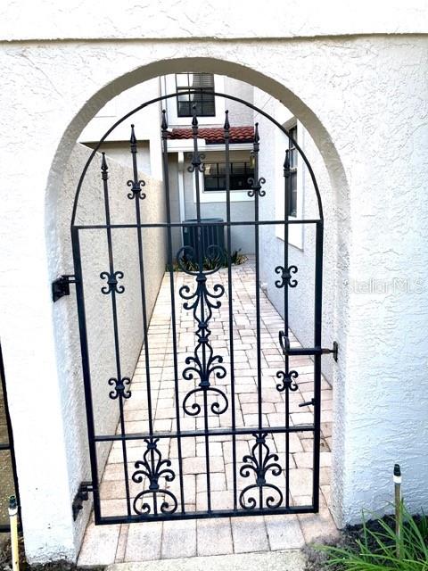 A black wrought iron gate stands within a stucco archway leading to a paved walkway — 8214 AMBROSE COVE WAY, ORLANDO, FL