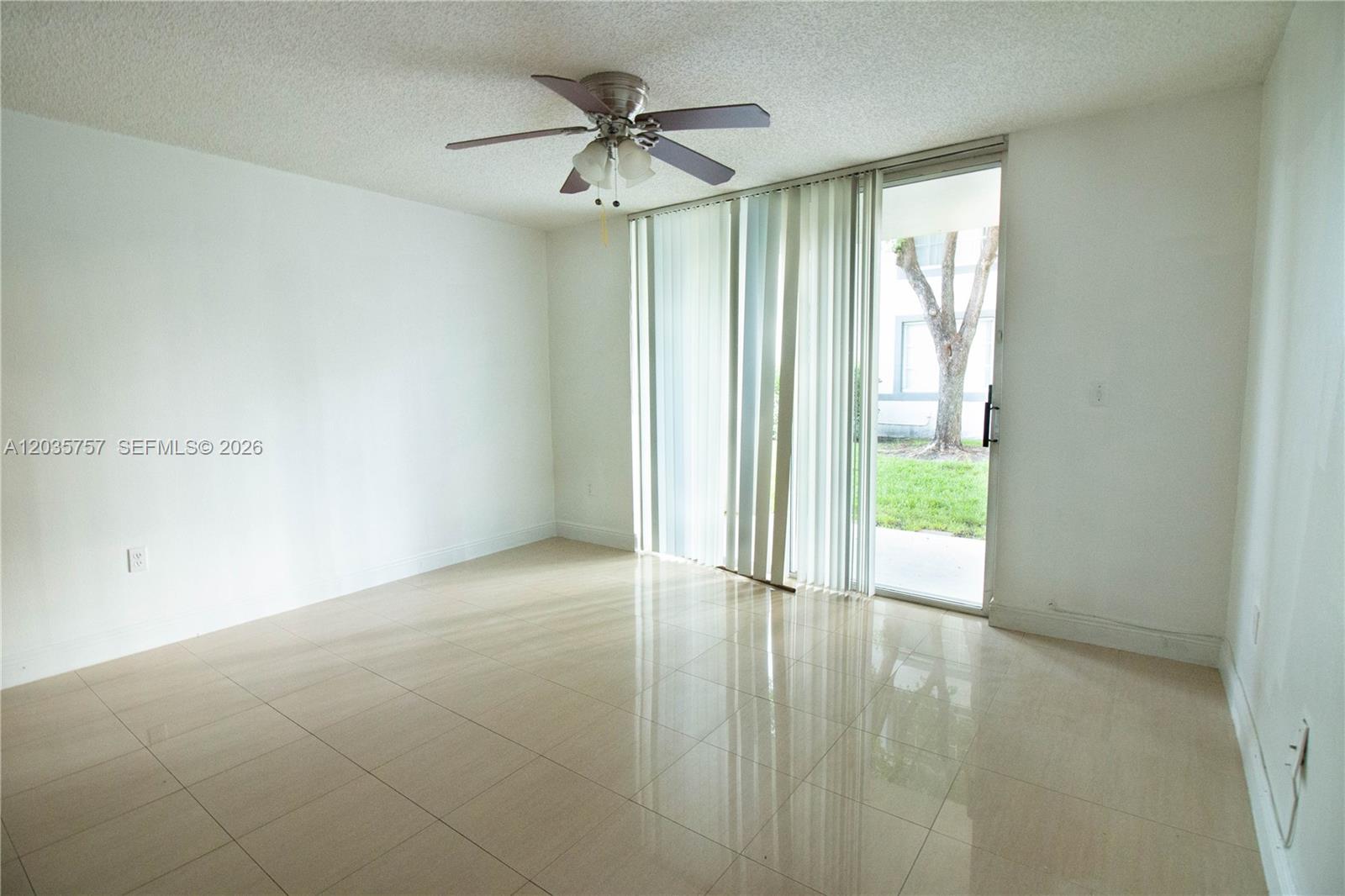 An empty room with tile flooring, a ceiling fan, and sliding glass doors to a patio — 4500 NW 107th Ave # 9, Doral FL 33178, DORAL, FL