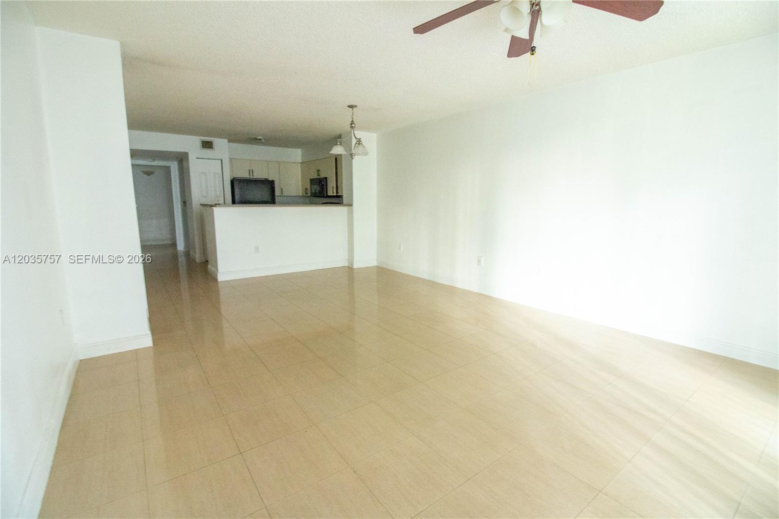 An open-concept living area features light-colored tile flooring, white walls, and an adjacent kitchen — 4500 NW 107th Ave # 9, Doral FL 33178, DORAL, FL