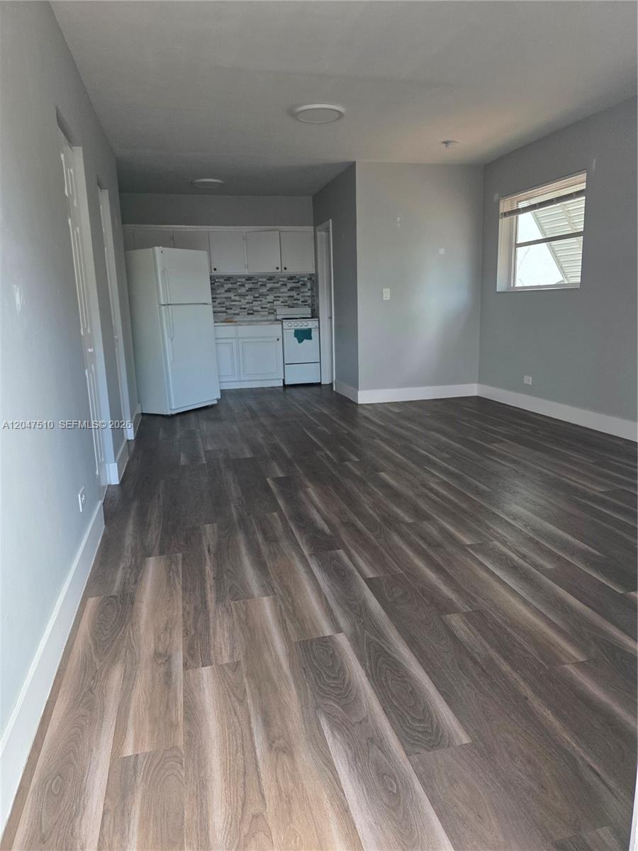This room features gray walls, wood-look flooring, and an open kitchen with white cabinets — 15 Esplanade Dr # B, Miami Springs FL 33166, MIAMI SPRINGS, FL