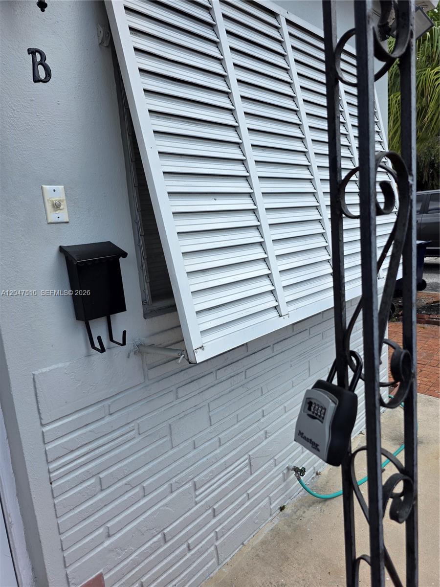 A white exterior wall features a louvered shutter, a black mailbox, and a lockbox — 15 Esplanade Dr # B, Miami Springs FL 33166, MIAMI SPRINGS, FL
