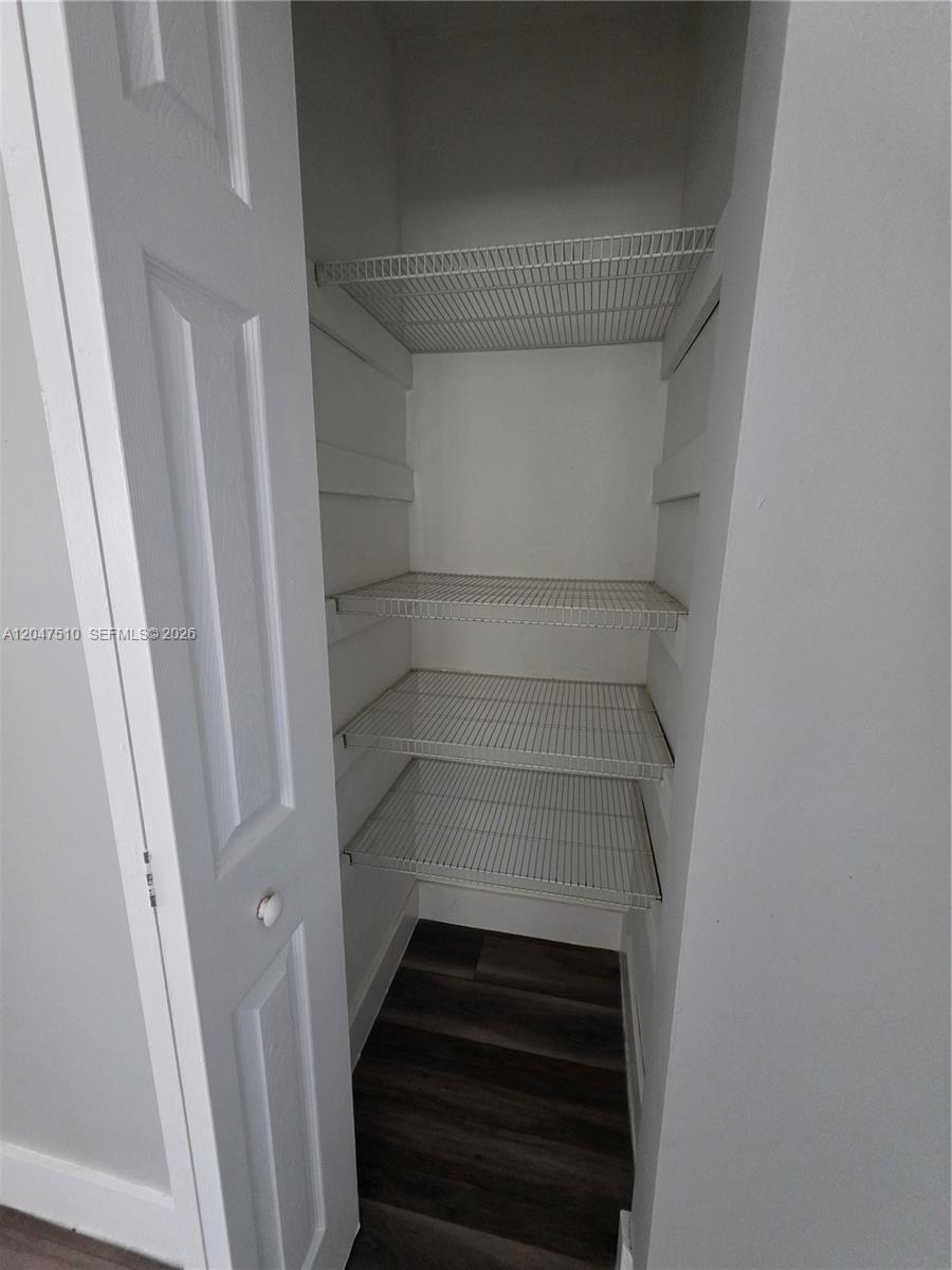 A white closet features three wire shelves and dark wood-look flooring — 15 Esplanade Dr # B, Miami Springs FL 33166, MIAMI SPRINGS, FL
