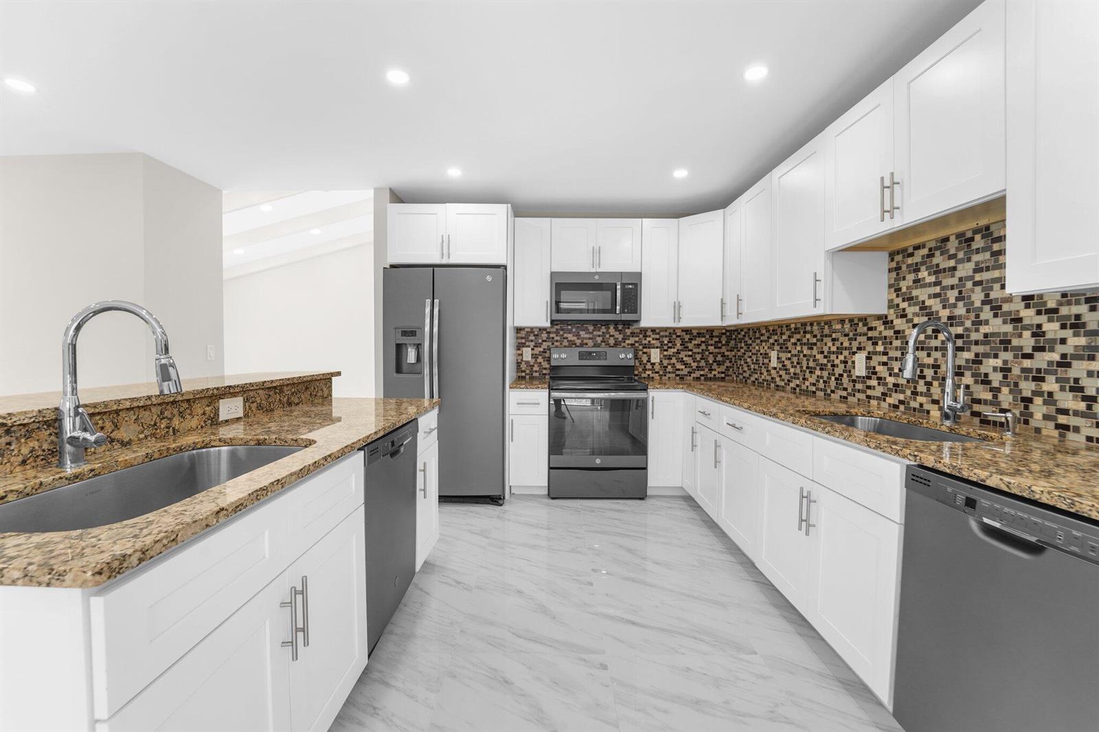 A kitchen with white cabinets, granite countertops, stainless steel appliances, and a mosaic tile backsplash — 22207 Alyssum Way, Boca Raton FL 33433, BOCA RATON, FL