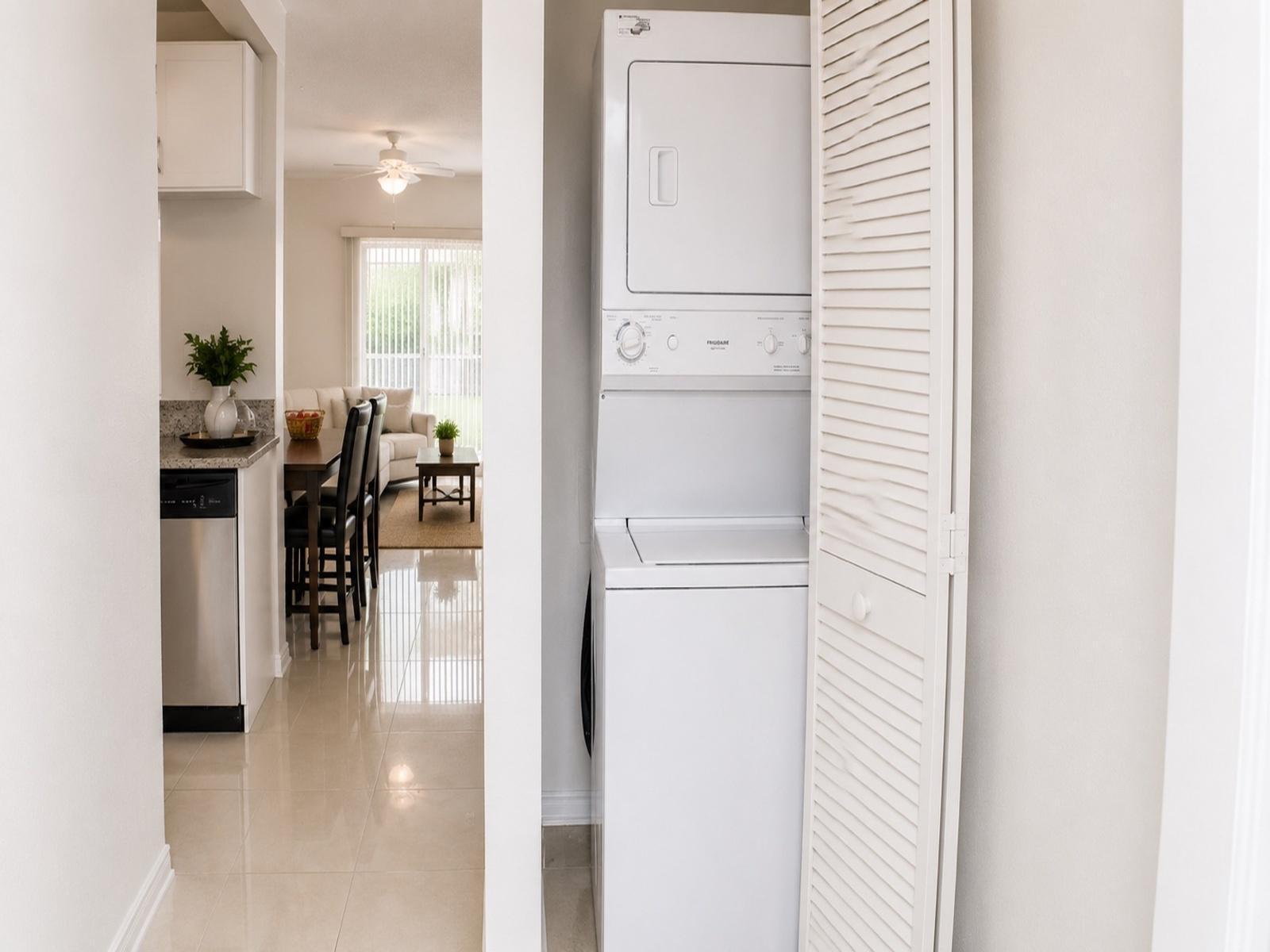 A stacked washer and dryer unit sits in a closet next to a modern kitchen — 75 Whitehead Circle # 75, Weston FL 33326, WESTON, FL
